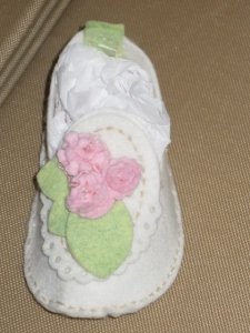 White felt baby bootie, with pink and pale green embellishments
